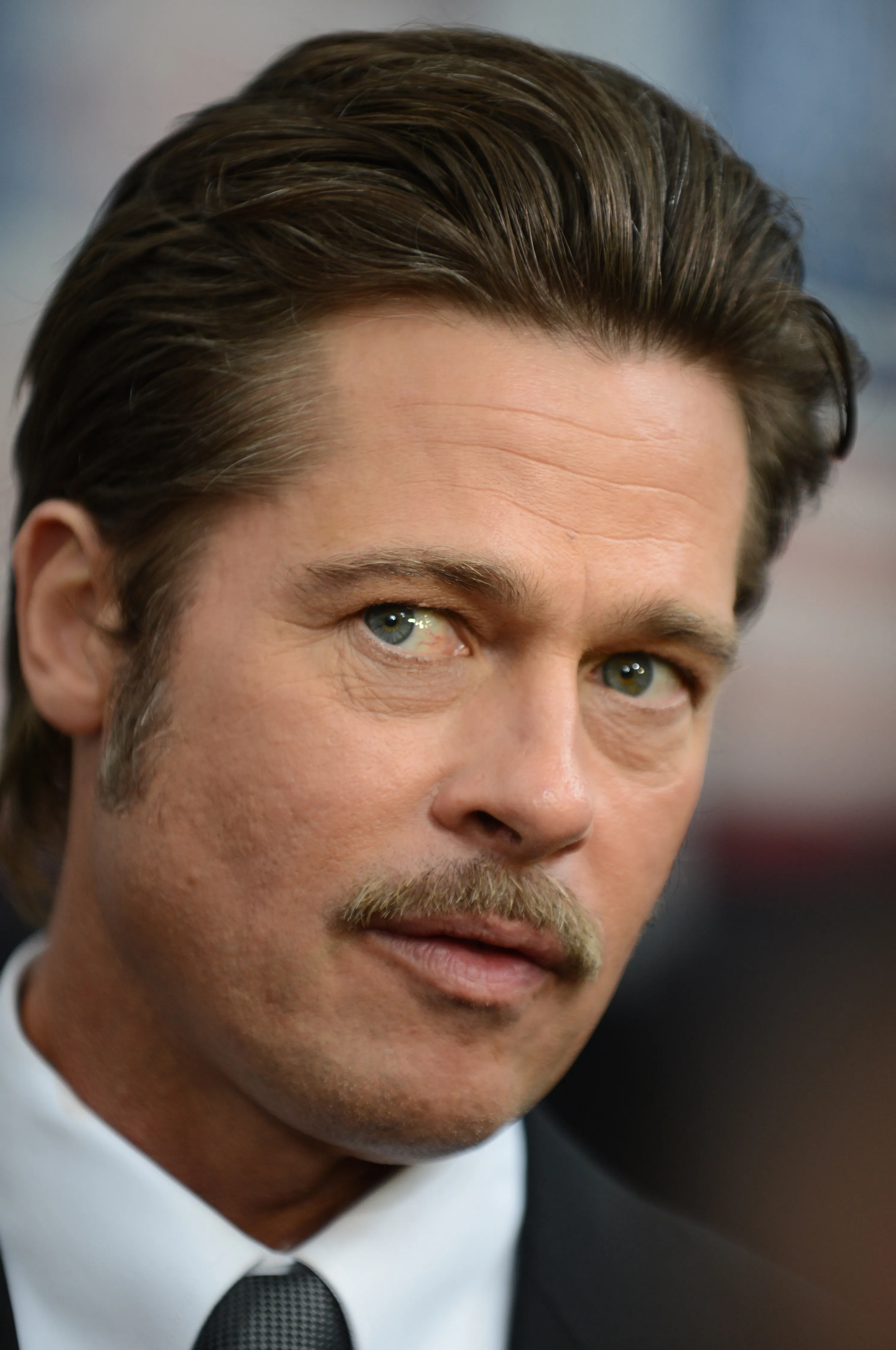 Brad Pitt at the Fury premiere in 2014, with medium-length hair brushed back and a tidy tapered outline.