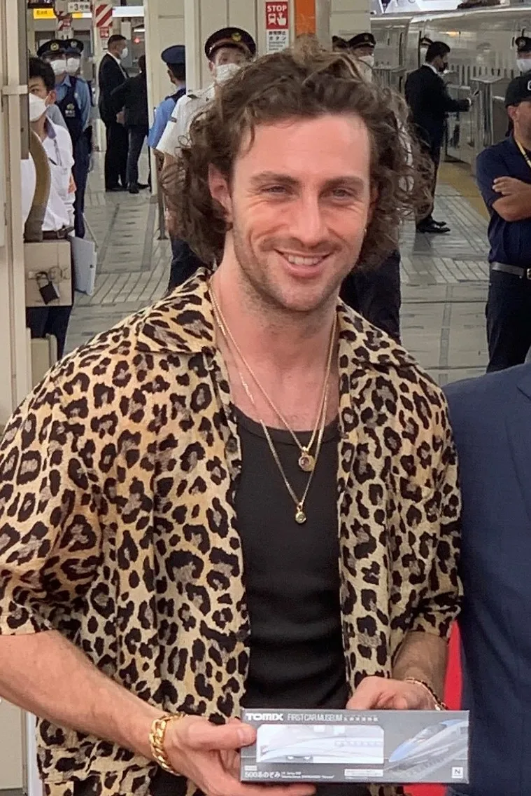 Brad Pitt at a Tokyo Station event in 2022, wearing grown-out loose curls brushed back from a relaxed near-center part.