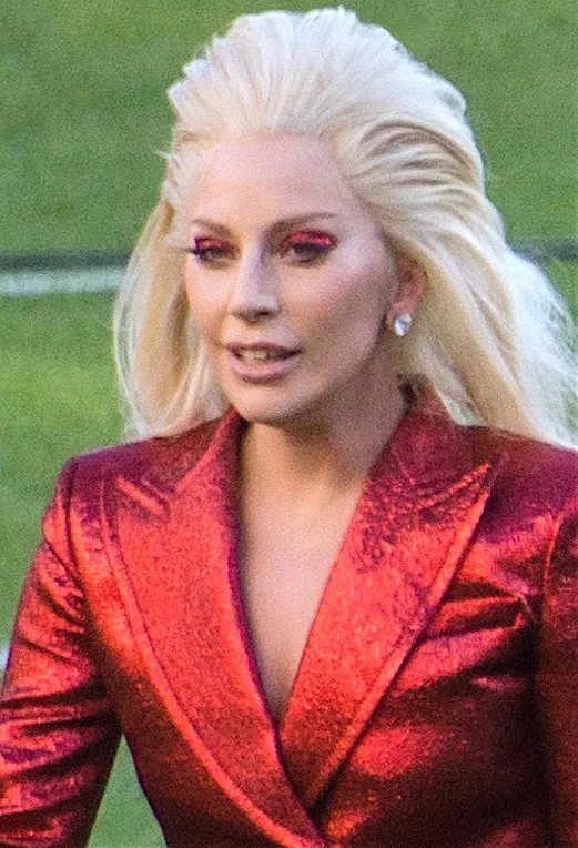Lady Gaga at the 2016 Super Bowl 50 National Anthem performance, wearing long platinum-blonde hair swept back with lift at the crown.