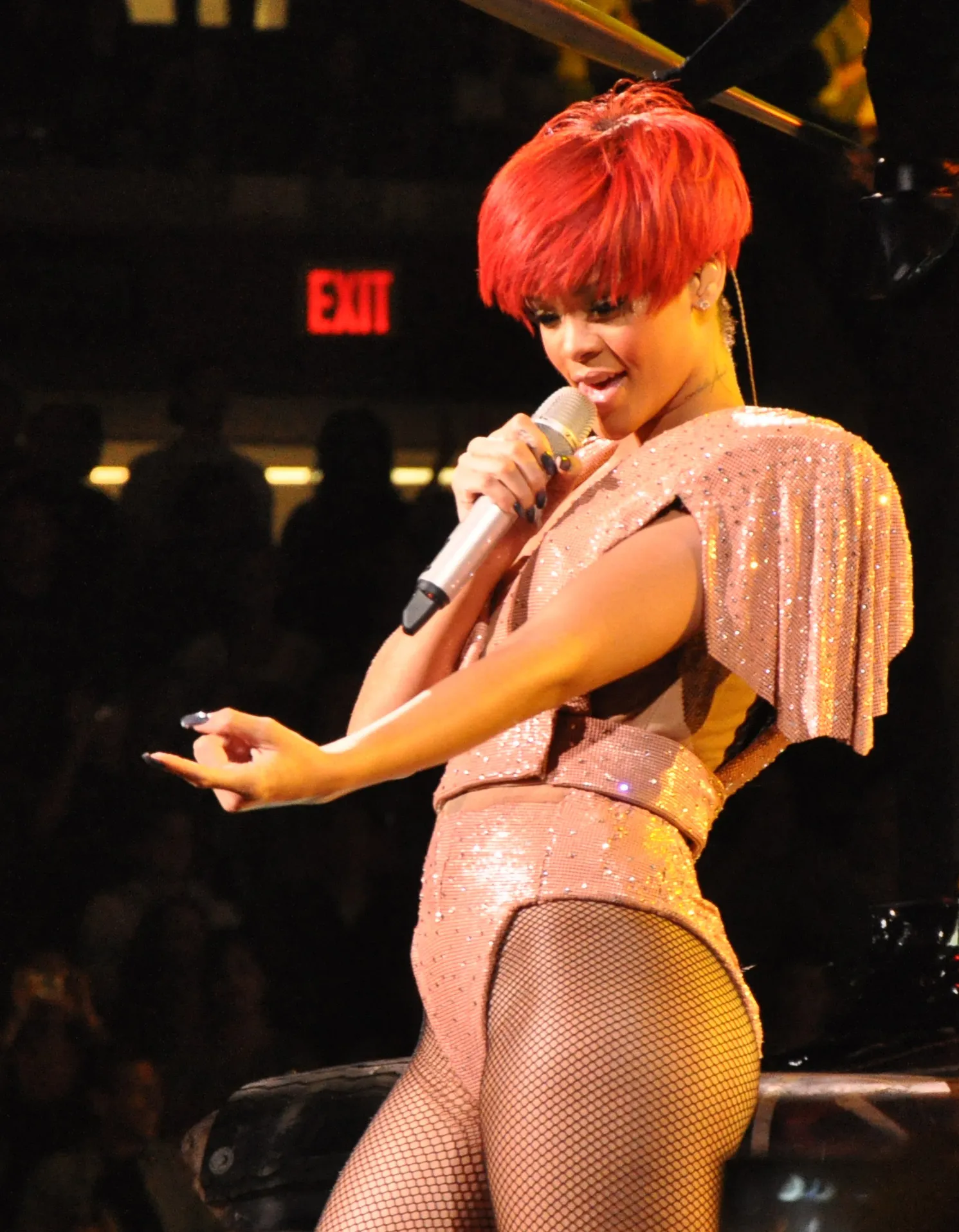 Rihanna performing during the Last Girl on Earth Tour on 12 August 2010, wearing bright red short rounded hair with a heavy side-swept fringe.